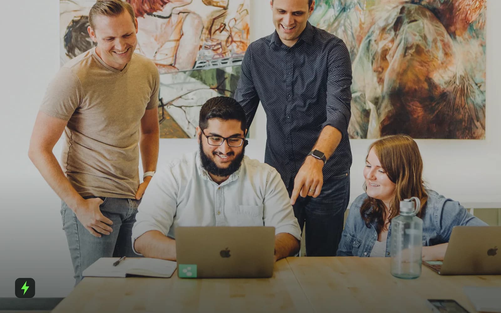 Four coworkers smiling around a laptop
